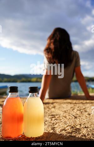 Thé kombucha cru fermenté maison avec différentes saveurs. Boisson probiotique naturelle saine avec une femme reposant en arrière-plan. Banque D'Images