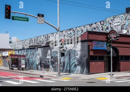 San Francisco, États-Unis - 04, 22, 2023 : feux de circulation et panneaux sur la route près du bâtiment avec graffiti sous un ciel bleu sans nuages Banque D'Images