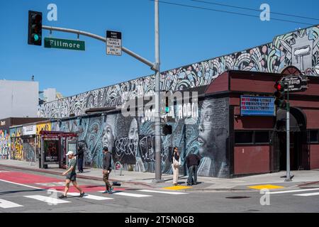 San Francisco, États-Unis - 04, 22, 2023 : feux de circulation et panneaux sur la route près du bâtiment avec graffiti sous un ciel bleu sans nuages Banque D'Images