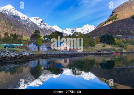 Paysage magnifique avec des montagnes et des cabanes en bois reflétées dans l'eau par le fjord Hjorundfjorden à Urke, Norvège, Scandinavie, Europe en octobre Sunnmøre Alpes Banque D'Images