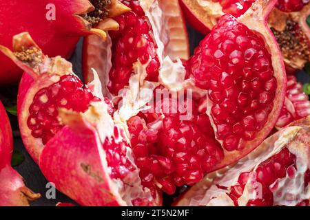 Fruits mûrs de grenade avec des tranches et des feuilles de grenade sur une table en pierre grise. Joli fond exotique de fruits pour vos projets. Banque D'Images