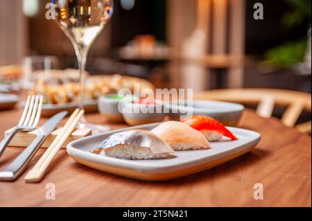 Nigiri set : maquereau, bar, saumon sur une assiette sur une table dans un bar à sushi sur une assiette en gros plan. Photo de haute qualité Banque D'Images