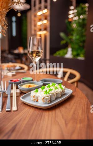 Rouleau de sushi avec fromage à la crème, graines de sésame et caviar de poisson volant vert sur une assiette en gros plan. Photo de haute qualité Banque D'Images