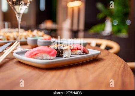 Nigiri set : thon, anguille et tataki de thon sur une assiette sur une table dans un bar à sushi sur une assiette gros plan. Photo de haute qualité Banque D'Images