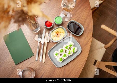 Rouleau de sushi avec fromage à la crème, graines de sésame et caviar de poisson volant vert sur une assiette en gros plan. Photo de haute qualité Banque D'Images