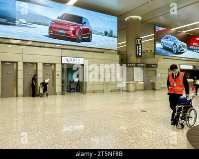 Shanghai, Chine, homme poussant le fauteuil roulant, vues intérieures de l'aéroport international de Hongqiao, affiches publicitaires pour les voitures électriques, à vendre, capitalisme chinois Banque D'Images