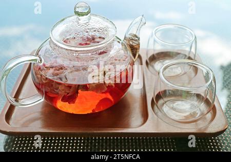 Gros plan d'un pot de thé d'infusion de rose avec une paire de tasses de thé Banque D'Images