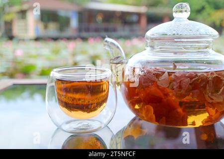 Gros plan d'une tasse de thé rose avec théière sur la table de jardin Banque D'Images