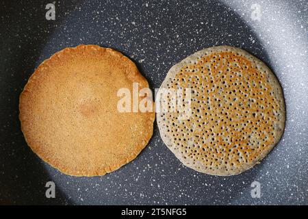 Paire de crêpes de blé entier avec graines de sésame noir moulu frit dans une poêle à frire Banque D'Images