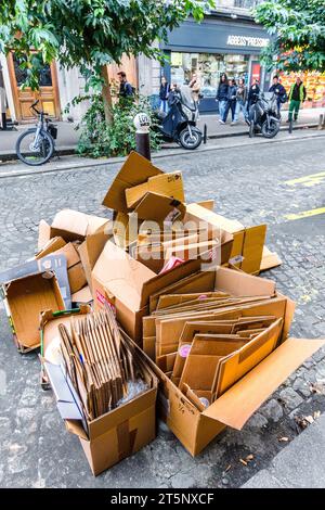 Boîtes de déchets en carton en attente de collecte pour recyclage le long de la rue des Abbesses à Montmartre, Paris 18, France. Banque D'Images