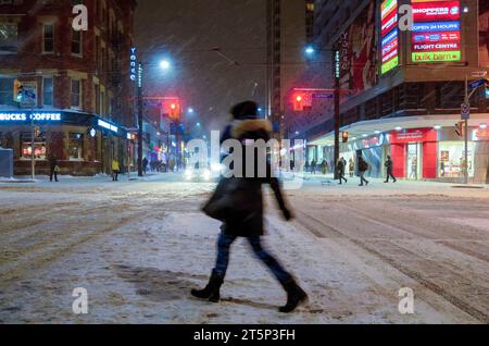 Toronto, Canada - 14 décembre 2013 : une personne traversant une rue du centre-ville pendant une tempête de neige pendant la saison hivernale Banque D'Images