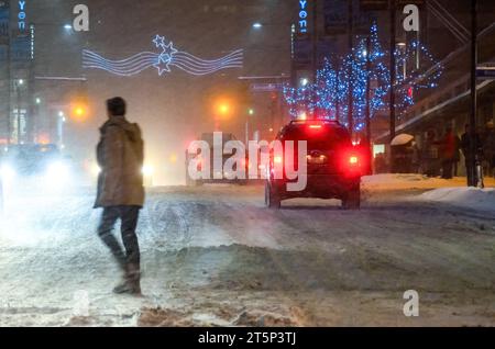 Toronto, Canada - 14 décembre 2013 : flou de mouvement d'une personne traversant une rue du centre-ville pendant une tempête de neige Banque D'Images