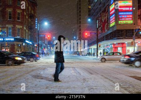 Toronto, Canada - 14 décembre 2013 : flou de mouvement d'une personne traversant une rue pendant une tempête de neige dans le quartier du centre-ville. Banque D'Images