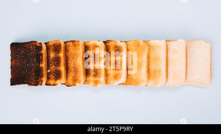 Vue de dessus tranches de pain différentes étapes griller des rangées disposées sur fond blanc Banque D'Images
