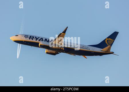 Un Boeing 737-8 Max de Ryanair, immatriculé EI-HGT au départ de Manchester (MAN.) un soir avec les traînées d'un autre avion au loin Banque D'Images