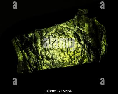 Moldavite Pierre en gros plan. Isolé sur fond noir. Pierre précieuse de tektite verte tchèque. Banque D'Images