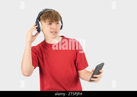 Portrait en studio d'un adolescent souriant de quinze ans en écoutant de la musique via son téléphone Banque D'Images