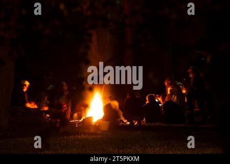 Les gens autour d'un feu de camp la nuit. Banque D'Images