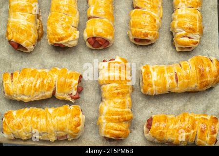 Gros plan de saucisses cuites dans la pâte sur du papier sulfurisé. Cuisson des saucisses dans la pâte à la maison. Banque D'Images