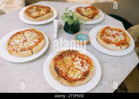 Pizza Margherita coupée en quatre morceaux repose sur des assiettes sur la table Banque D'Images