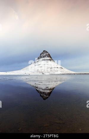 Kirkjufell, nunatak colline couverte de neige reflétée dans l'eau du fjord sur la péninsule de Snæfellsnes en hiver, montagne la plus photographiée en Islande Banque D'Images