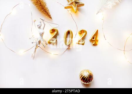 Chiffres de l'année 2024 à partir de chiffres volumineux en or sur fond blanc. Nouvel an. Concept de danse. Jouet ballerine et Noël décoratif artificiel Banque D'Images