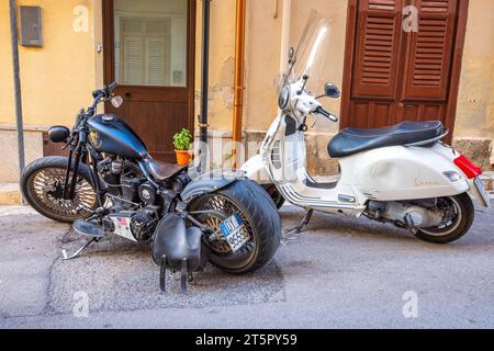 CASTELLAMMARE DEL GOLFO, ITALIE - 15 JUILLET 2023 : Harley Davidson et Vespa motos dans une rue. Banque D'Images