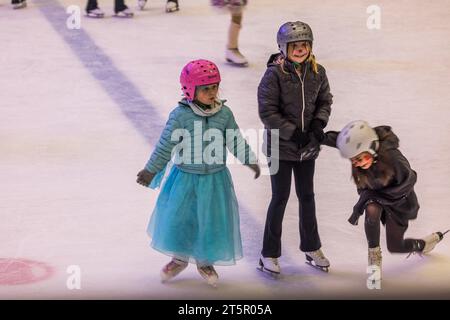 Joyeuses jeunes filles en costumes de fantaisie avec des visages peints prêts pour la fête d'Halloween sur la patinoire. Banque D'Images