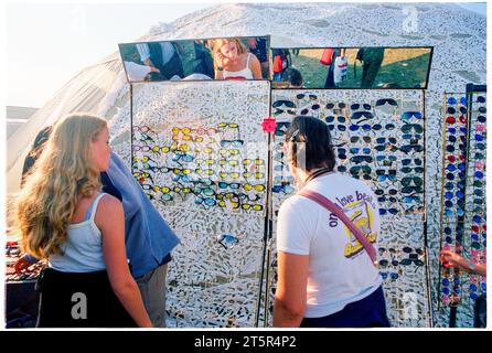 FANS DE BRITPOP et ROCK, READING FESTIVAL, 1998 : deux amis achètent des lunettes de soleil sur les stands du terrain principal. Une scène du site et de la foule dans la zone main Stage Arena au Reading Festival 1998 le 28-30 août 1998 à Reading, Angleterre Royaume-Uni. Photo : Rob Watkins Banque D'Images