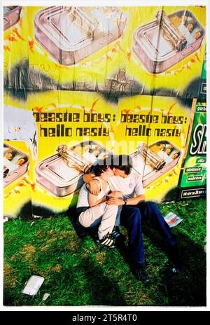 YOUNG LOVE, FANS DE BRITPOP et ROCK, READING FESTIVAL, 1998 : un jeune couple partage un baiser romantique sous une affiche Beastie Boys sur le côté de la scène. Une scène du site et de la foule dans la zone main Stage Arena au Reading Festival 1998 le 28-30 août 1998 à Reading, Angleterre Royaume-Uni. Photo : Rob Watkins Banque D'Images