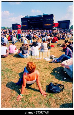 FANS DE BRITPOP et DE ROCK, READING FESTIVAL, 1998 : une jeune femme profite d’un moment de détente près de la scène principale sous le soleil chaud. Une scène du site et de la foule dans la zone main Stage Arena au Reading Festival 1998 le 28-30 août 1998 à Reading, Angleterre Royaume-Uni. Photo : Rob Watkins Banque D'Images