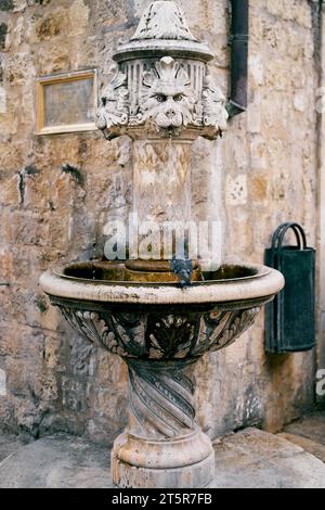 Ancienne fontaine médiévale en pierre au coin du bâtiment. Dubrovnik, Croatie Banque D'Images