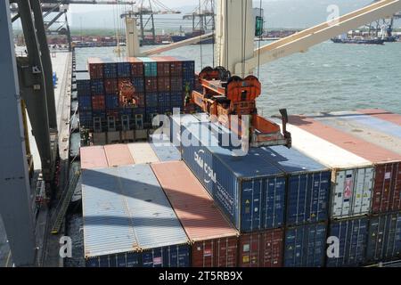 Epandeur de grue à portique actionné par des débardeurs approchant le conteneur pour le décharger d'un navire. Banque D'Images