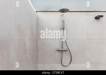Pomme de douche en acier inoxydable dans une douche extérieure Banque D'Images