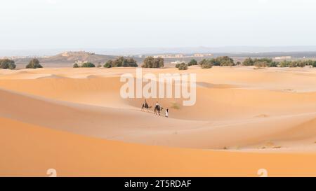 Désert du Sahara, Maroc - 13 septembre 2022 : touristes sur une promenade à dos de chameau à travers les dunes de sable guidés par un Berbère, un exp touristique classique du désert du Sahara Banque D'Images