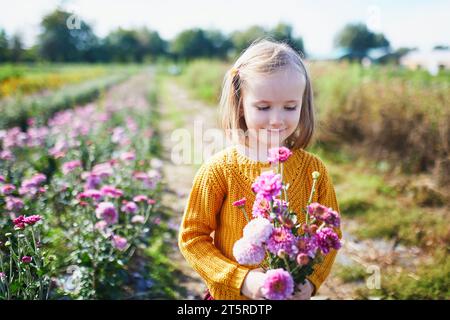 Adorable fille cueillant de belles fleurs marguerite à la ferme. Activités estivales en plein air pour les petits enfants Banque D'Images