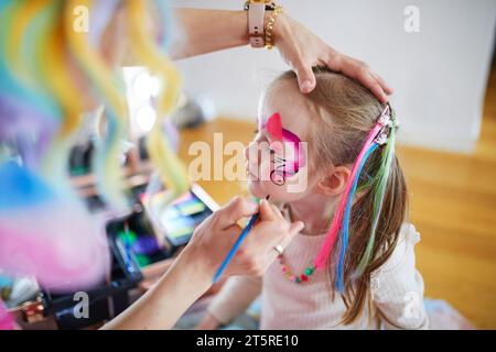 Peinture de visage d'enfants. Artiste peignant petite fille d'enfant d'âge préscolaire comme licorne sur une fête d'anniversaire. Activités créatives pour les enfants Banque D'Images