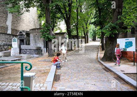 Paris, France. Juin 30 2022. Belle vue sur l'avenue d'entrée du cimetière historique du Père-Lachaise. Les gens marchent le long de l'avenue bordée d'arbres Banque D'Images