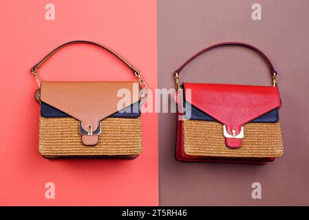 Deux sacs pour femmes tissés tendance avec le même design mais avec des rabats en cuir de différentes couleurs affichés sur un fond rouge-brun contrastant. CR Banque D'Images