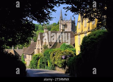 Castle Combe : Église St Andrew, Cotswold cottages en pierre et Wisteria en fleurs dans le village de Castle Combe, Cotswolds, Wiltshire, Angleterre, Royaume-Uni Banque D'Images