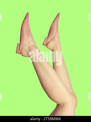 Jambes de femme en tongs roses tendance, isolées sur un fond vert, à l'envers. Concept de soldes d'été pour chaussures. Affiche publicitaire créative Banque D'Images