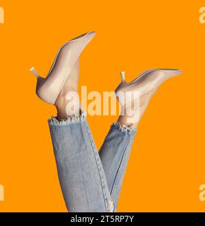 Photo funky des jambes d'une femme portant des escarpins et des jeans pastel tendance, à l'envers, isolés sur un fond orange vif. Campagne de marketing pour selli Banque D'Images
