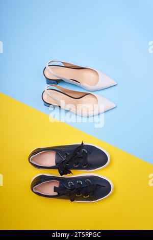 Une vue de dessus de deux paires de chaussures tendance féminines : escarpins blancs ouverts à dos avec talons noirs et baskets bleues marine décontractées sur un fond bicolore. Fash Banque D'Images