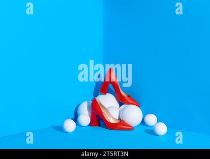 Une photo de studio de chaussures pour femmes rouges classiques placées dans le coin de l'espace de couleur bleue sur des sphères blanches. Blog de mode ou concept de magazine. Espace de copie. Banque D'Images