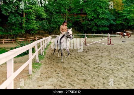 Cheval gris dapple à l'hippodrome par jockey femelle. Femme équestre prenant des leçons d'équitation à l'école de cheval. Dressage de chevaux, dressage de chevaux, trott Banque D'Images