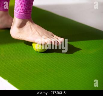 Une balle de tennis sous le pied féminin. Massage pour soulager la tension musculaire, améliorer la circulation et soulager la fasciite plantaire. Physiothérapie, réflexologie, Banque D'Images