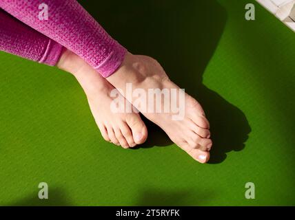 Après avoir reçu un massage pour soulager le stress musculaire, les pieds d'une femme se détendent sur un tapis de yoga vert. Réduisant les douleurs musculaires, augmentant le flux sanguin. PH Banque D'Images