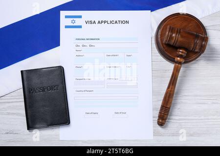 Immigration en Israël. Formulaire de demande de visa, marteau, passeport et drapeau sur table en bois blanc, pose à plat Banque D'Images