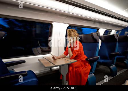 Jeune jolie femme d'affaires voyageant par le train classique français assis près de la fenêtre et en utilisant smartphone traveving de Paris à son pays natal Banque D'Images