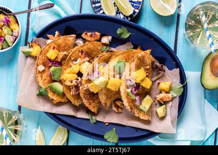 Tacos de poisson croustillants faits maison garnis d'une salsa à la mangue et à l'avocat. Banque D'Images